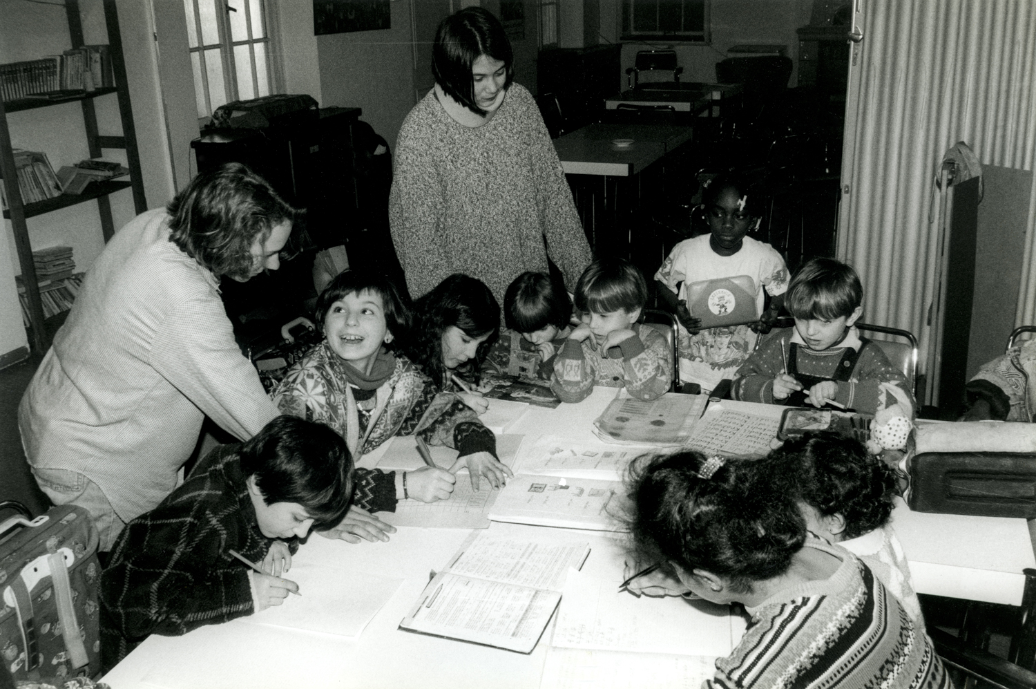 Schwarz Weiß Foto von sechs Kindern bei der Hausaufgabenhillfe